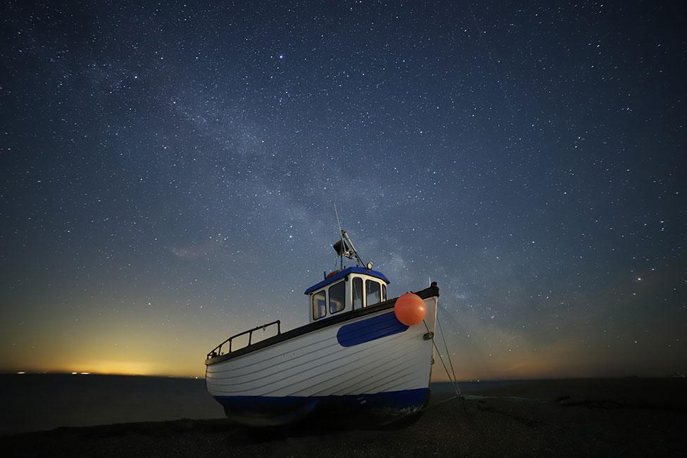 A fishing boat seen on the water beneath a night sky