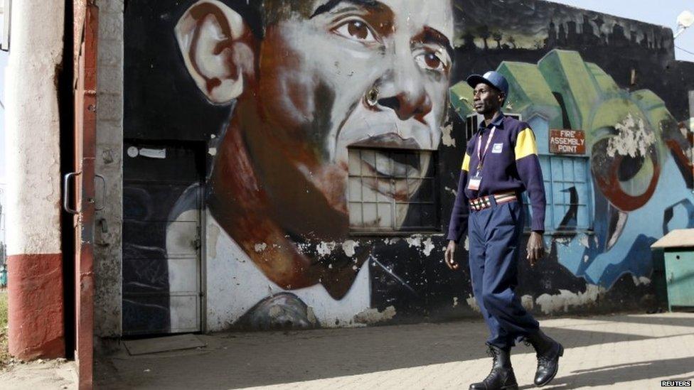 A security guard walks past a wall mural depicting U.S. President Barack Obama outside the Go-Down Art Centre in Kenya"s capital Nairobi