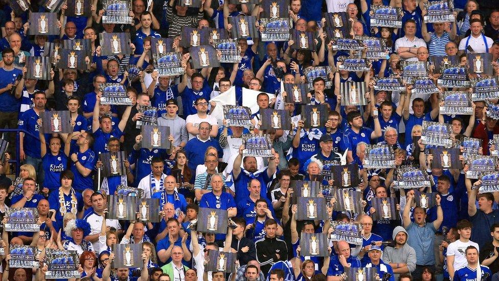 Leicester City fans raise aloft pictures of the Premier League trophy