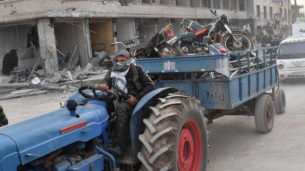 A Turkish-backed Syrian rebel fighter tows looted items in the Syrian city of Afrin (18 March 2018)