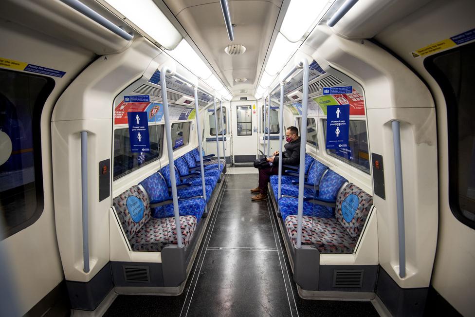 A commuter travelling on a deserted Jubilee Line London Underground train