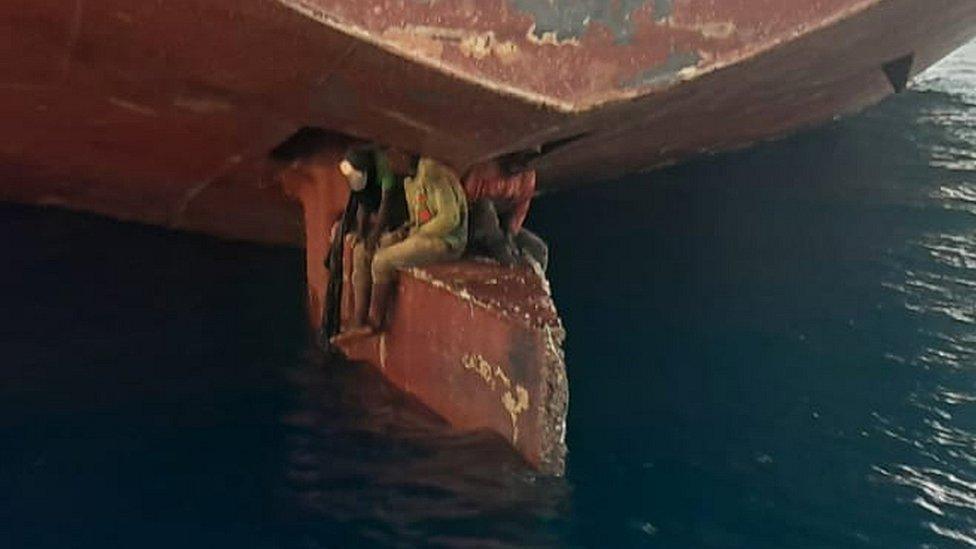 Three people sitting on a ship's rudder