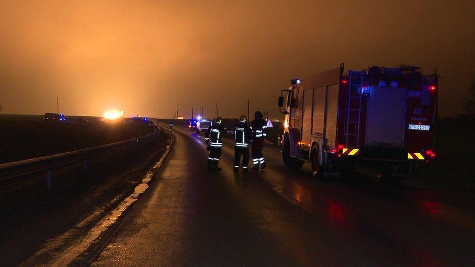 Firefighters look from a distance at fireball