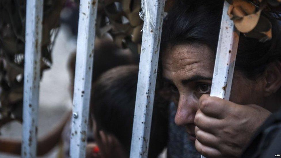 Migrants behind a fence as they arrive at the refugee centre in the town of Presevo, after walking from Macedonia to Serbia (26 August 2015)