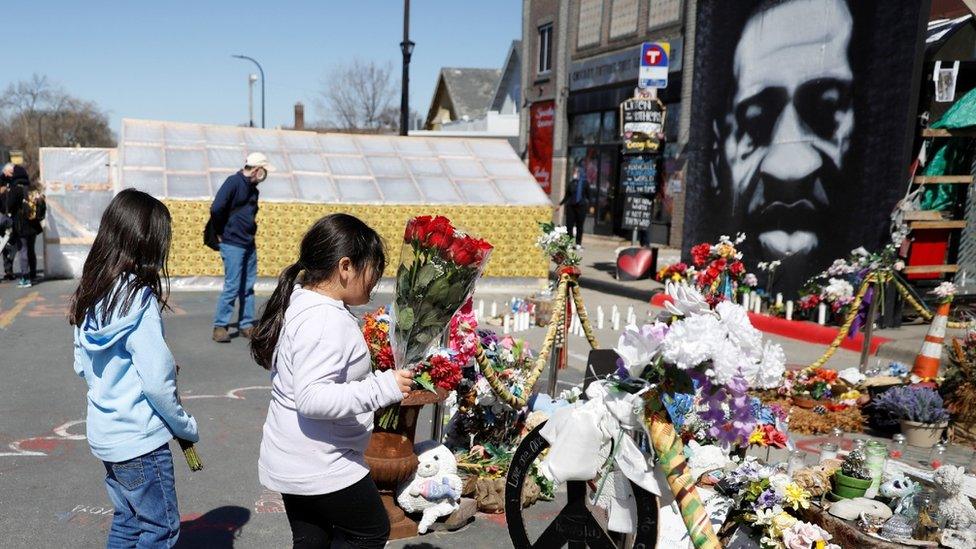 Obije Native American tribal members Ava Warrior-Graves (L) and her sister Malaysia Haro place tobacco leaves flowers at George Floyd Square