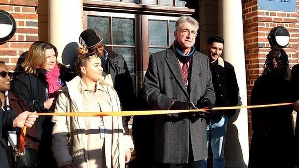 Reading mayor Tony Page is surrounded by people as he cuts a ribbon at the front door of a block of flats