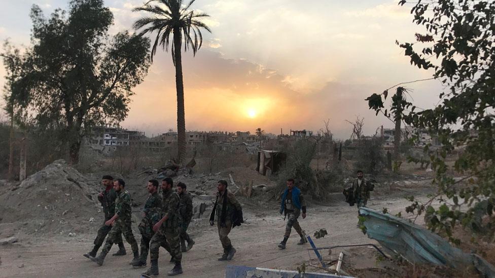 Syrian government forces walk through a road in a north-eastern district of Deir al-Zour