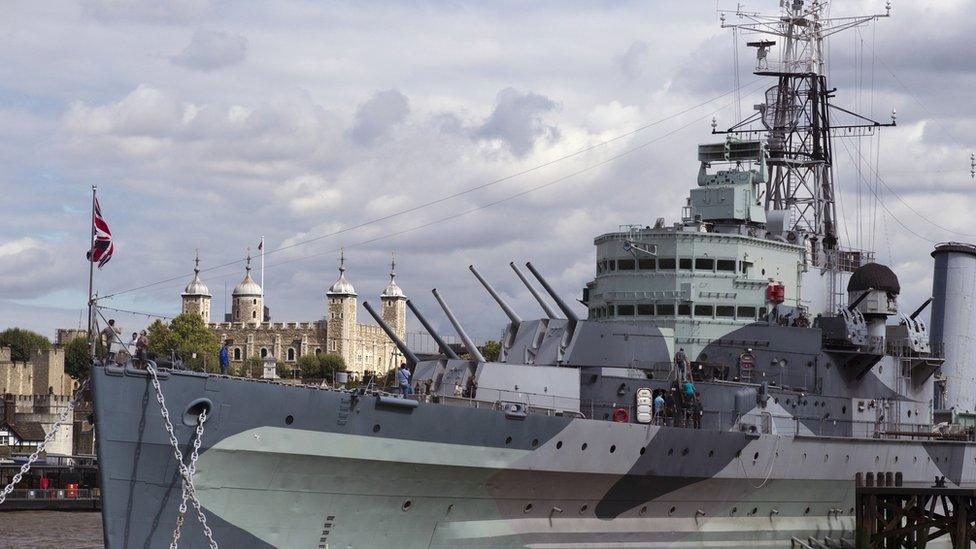 The HMS Belfast pictured on the River Thames in London on a clear day, with a union flag at its front