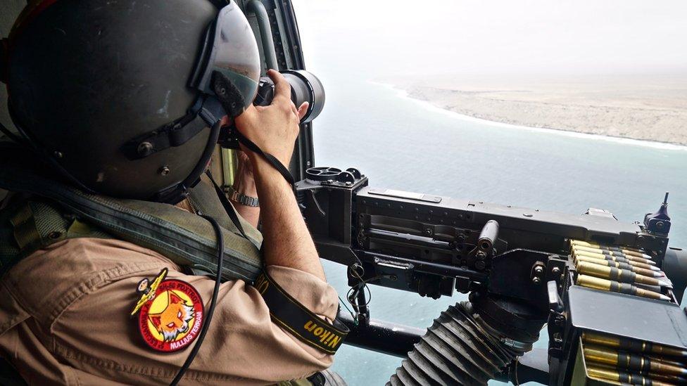 Man with a machine gun overlooking the sea