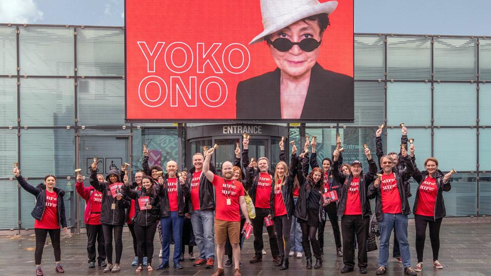 MIF volunteers in front of a screen showing Yoko Ono