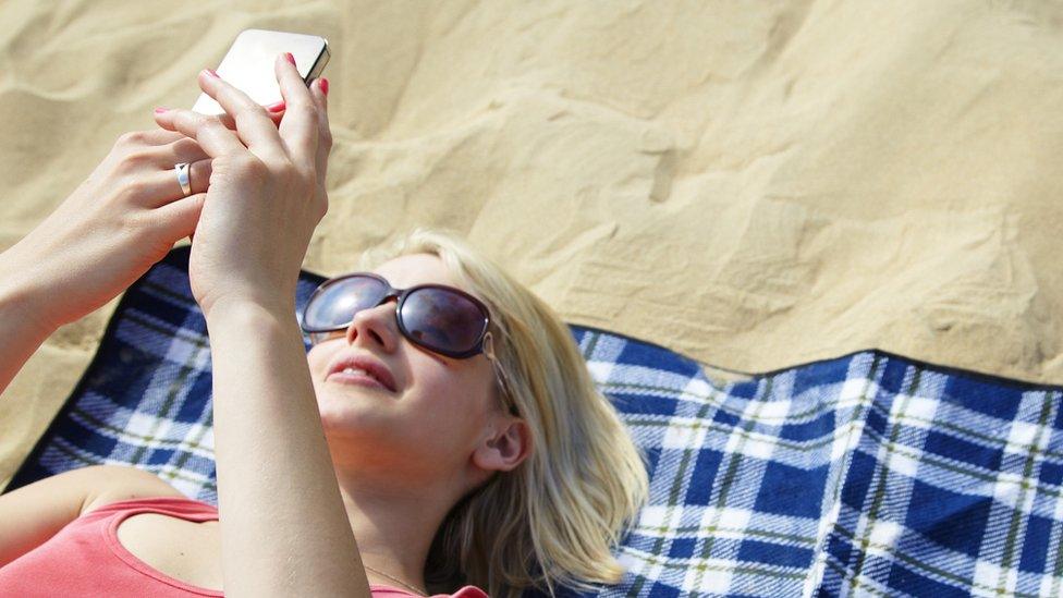 Woman lies on beach on towel