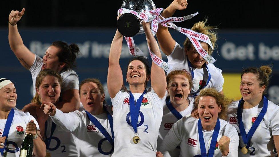 Sarah Hunter lifting a trophy with teammates behind her