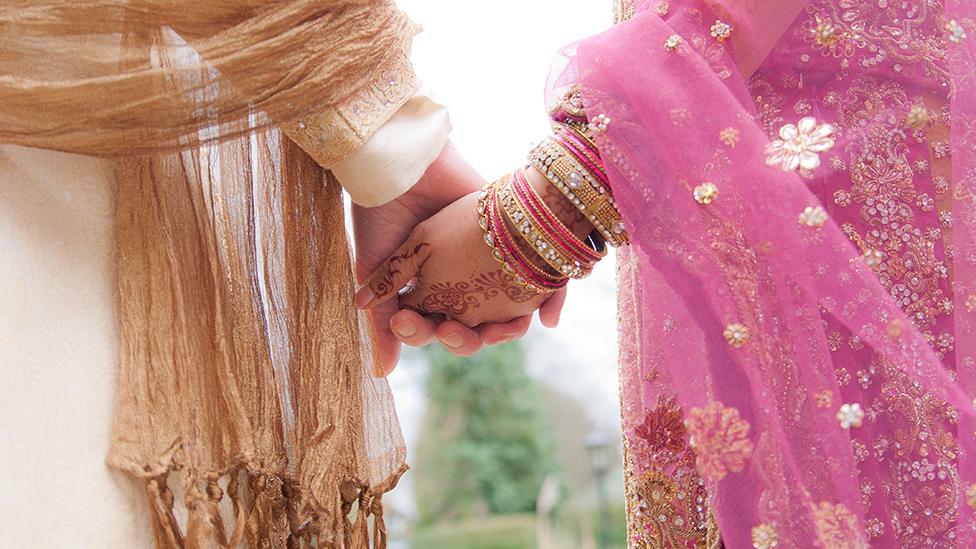 Muslim wedding - close up of bride and groom holding hands