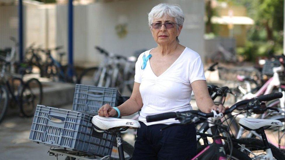 Vivian Silver in white T-shirt among bicycles