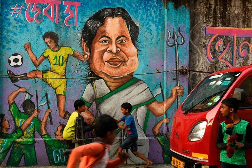 Children play in front of a wall graffiti depicting the Trinamool Congress (TMC) leader and West Bengal state chief minister Mamata Banerjee ahead of the state legislative assembly elections in Kolkata on February 27, 2021.