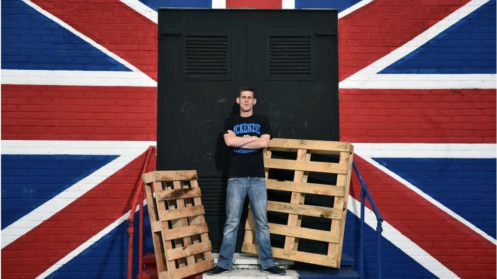 A man standing next to a union flag mural