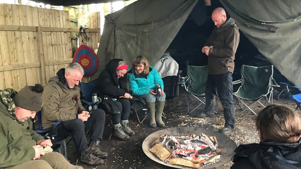 People sitting around a campfire during the day