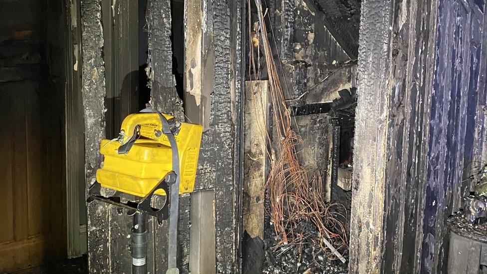 Burnt out door, charred remains of house.