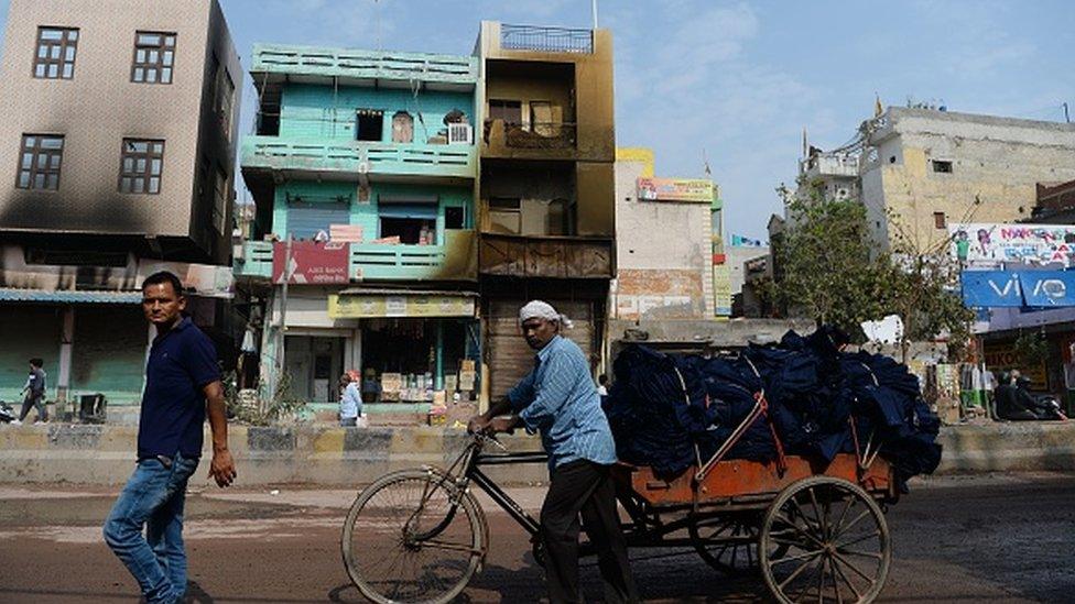 Resident walk past a building attacked during this week's sectarian riots over India's new citizenship law, in New Delhi on March 1, 2020.