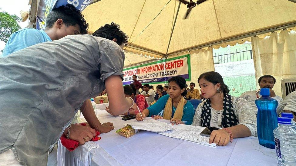 People check a list at a hospital in Cuttack to see if their relatives have been taken there