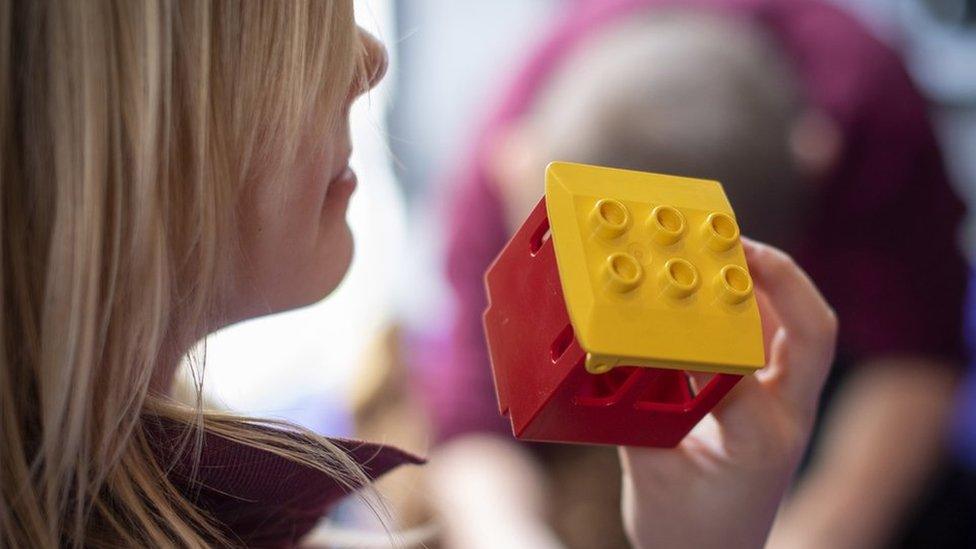 A girl holds a building block to her face