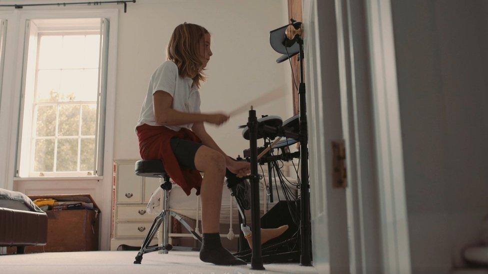 Euan playing a drum kit at home