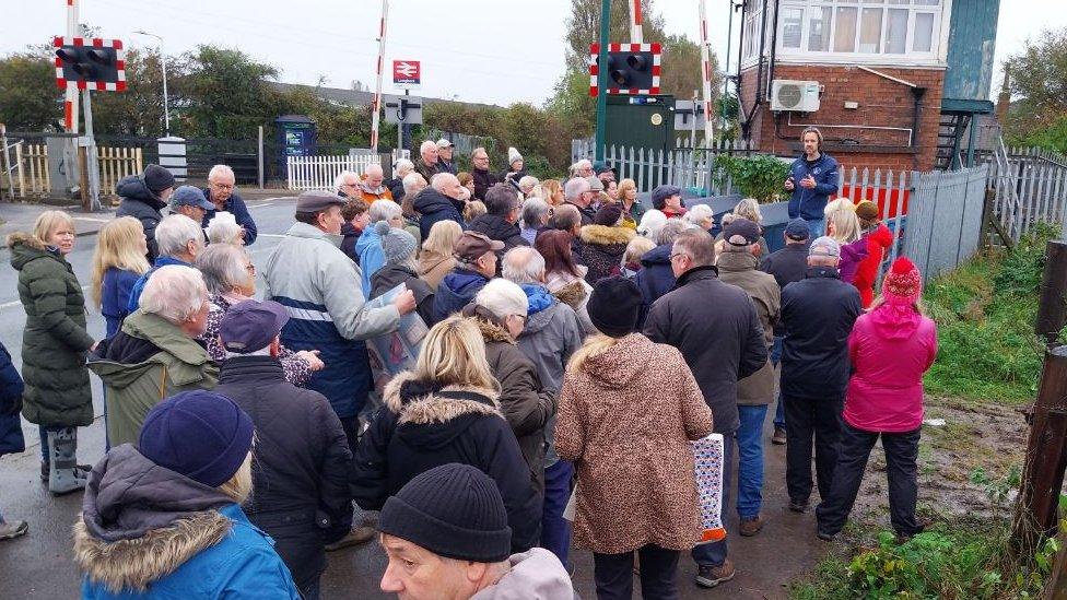 Man in sports jacket speaking to elderly protesters