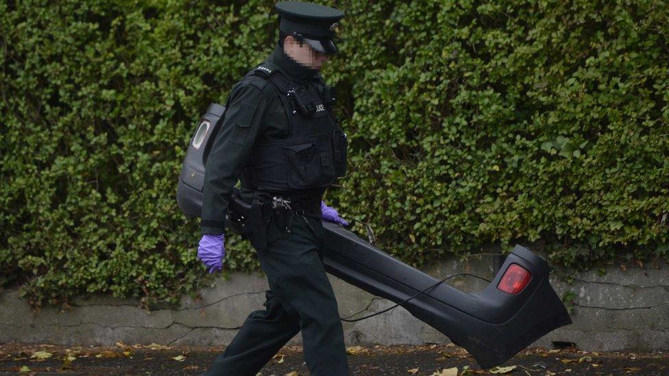 A police officer removes a bumper from the van that hit Enda Dolan from the scene of the crash on Belfast's Malone Road