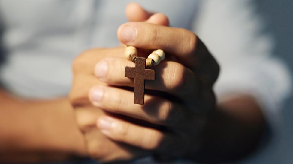 Stock photo of hands holding a rosary