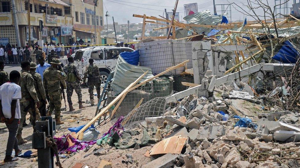 Somali security force personnel walk among debris at the site of a car bomb explosion near the building of the Interior Ministry in Mogadishu on July 7, 2018.