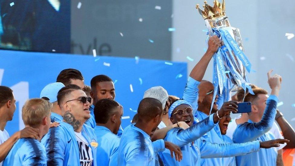 Manchester City players celebrate with the Premier League trophy