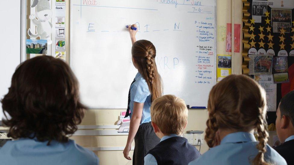 School child writing on blackboard