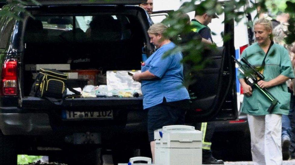 A woman carries a tranquilizer gun as members from the veterinary office search for the suspected lioness after police warned the public that it was on the loose, in Zehlendorf, Berlin