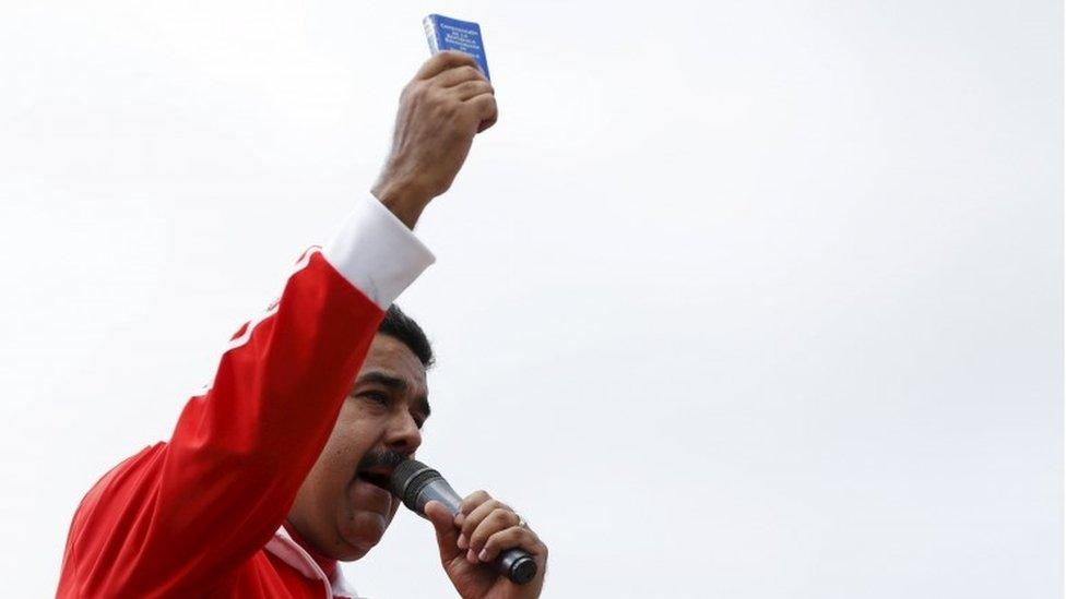 Venezuela's President Nicolas Maduro holds a copy of the country's constitution while he talks to supporters during a meeting outside Miraflores Palace in Caracas, December 15, 2015.