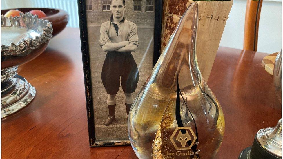 Glass award in front of a black and while photo of Joe Gardiner