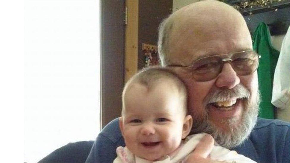 Man with glasses and grey beard holding baby