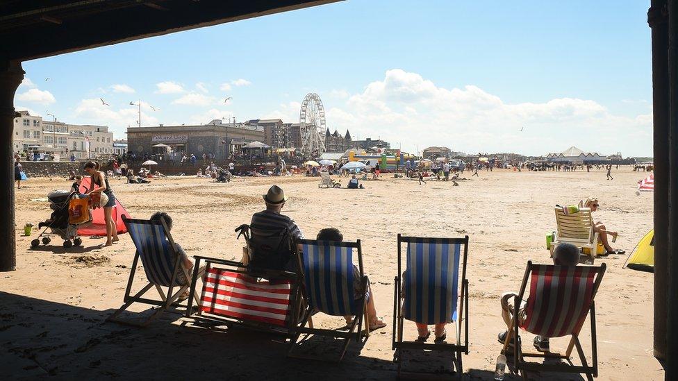 People relax under the pier on the beach at Weston-super-Mare