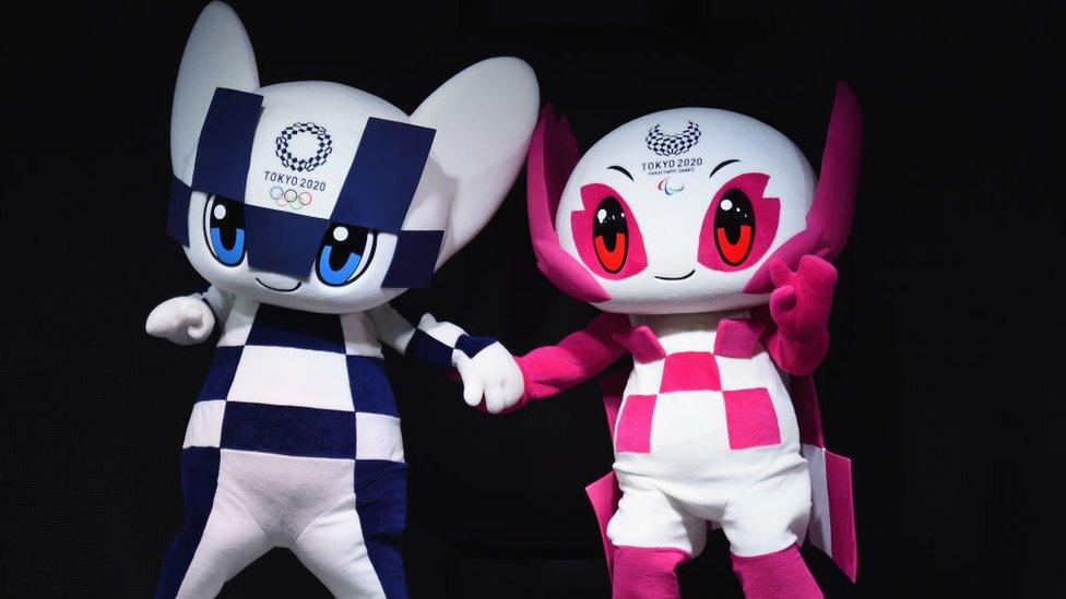 Miraitowa is a blue and white chequered mascot. Someity is a pink and white mascot