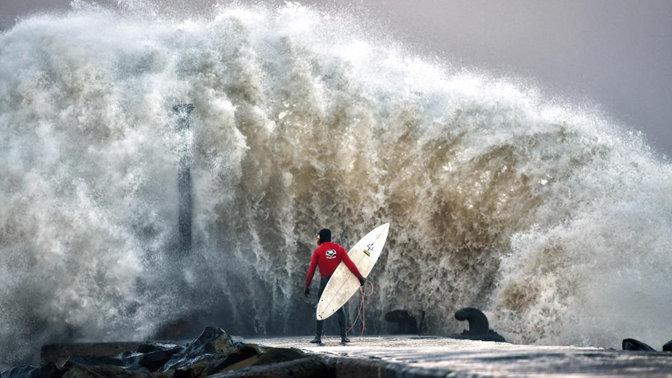 A huge wave crashes against Castlerock pier as professional surfer Al Mennie waits on a break in the swell on December 22 in Coleraine, Northern Ireland