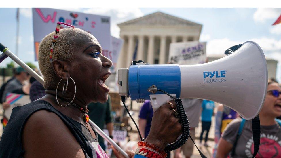 Woman with megaphone in front of Supreme Court