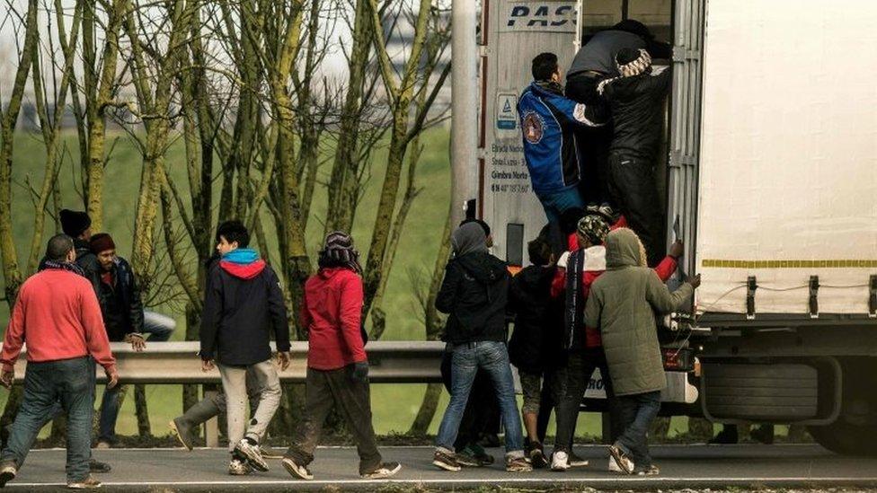 Migrants and refugees enter the trailer of a truck at the Eurotunnel site in Calais (17 December 2015)