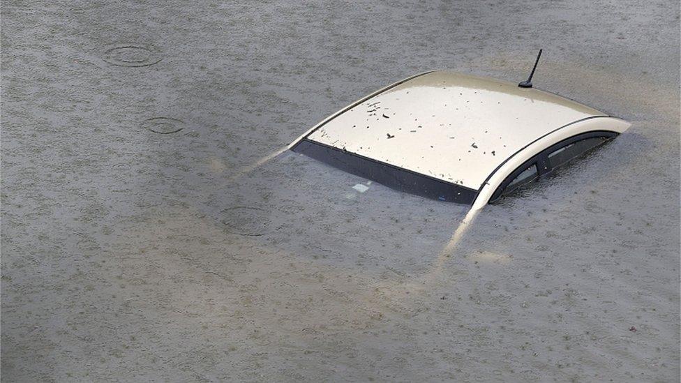 Car is pictured totally under water beneath pouring rain and floodwater