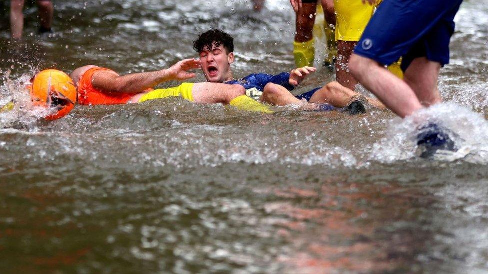 Footballers lying in a river