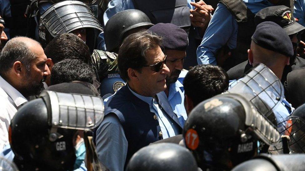 Police commandos escort former Pakistan's Prime Minister Imran Khan (C) as he arrives at the high court in Islamabad on May 12, 2023. (Photo by Aamir QURESHI / AFP)