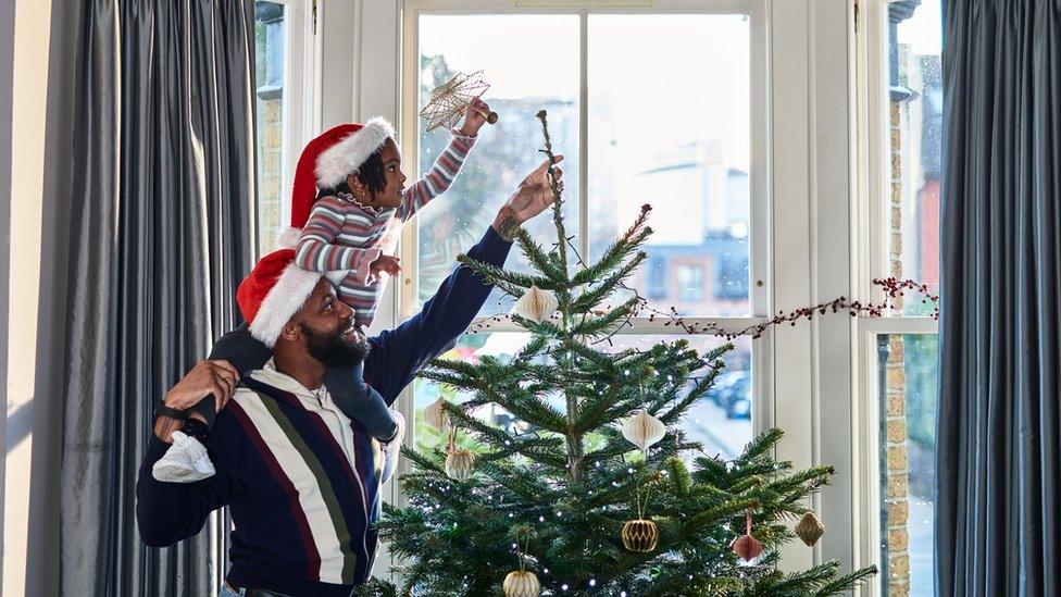 A man and a girl decorate a Christmas tree