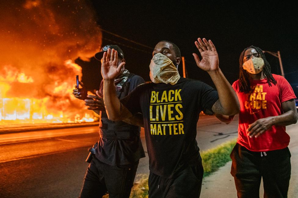 Men walk towards law enforcement with their hands up on 24 August 2020, in Kenosha, Wisconsin