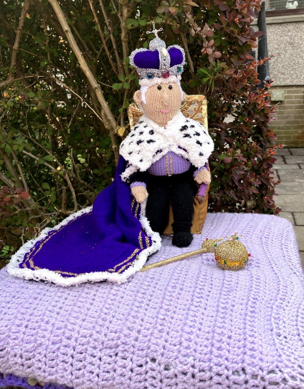 A very dapper knitted king sits on a golden knitted throne