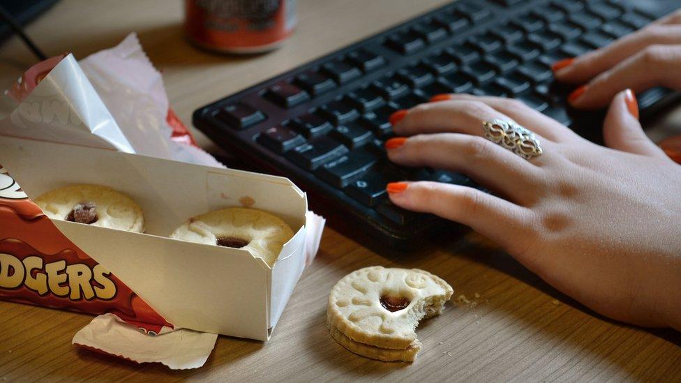 Woman eating biscuits at desk