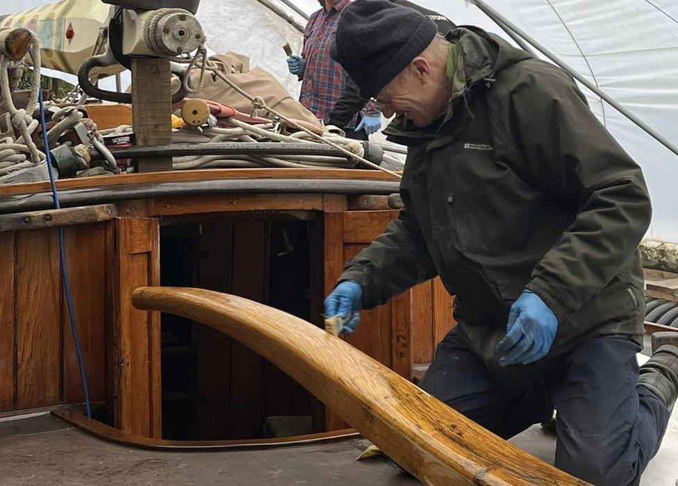 A volunteer varnishing part of one of the wherries