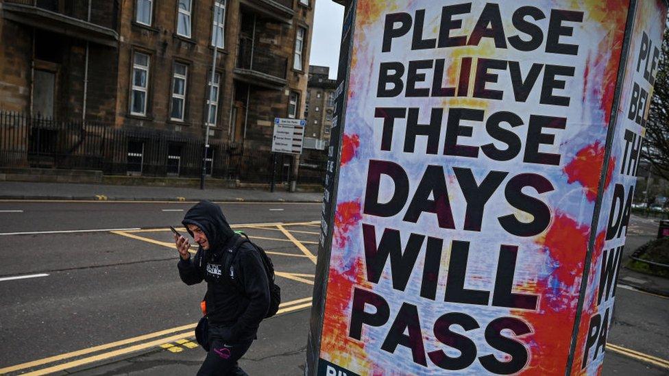 Man walks past a poster in Glasgow